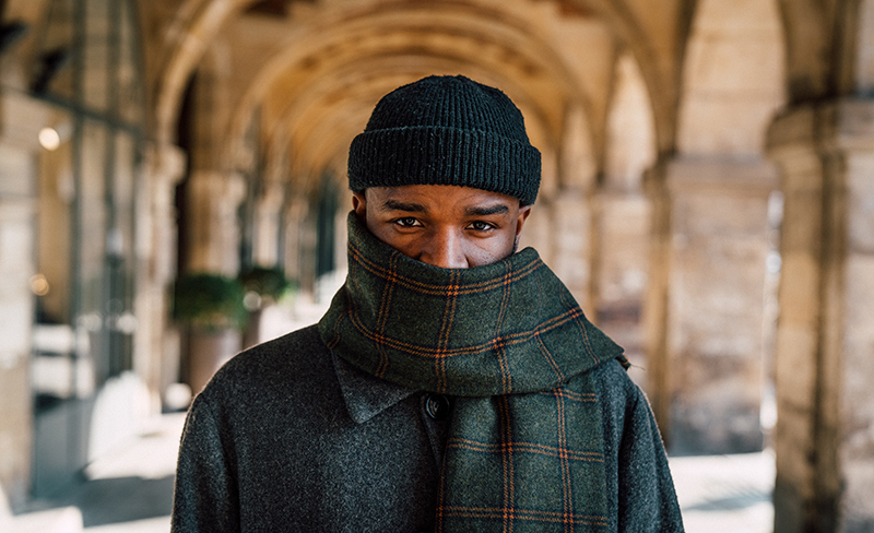 Man wearing a wool coat, a great scarf, and a knit winter hat.